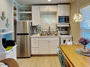 a kitchen with white cabinets and a stainless steel refrigerator at Harbor Lights Cottages 3 in Rockport