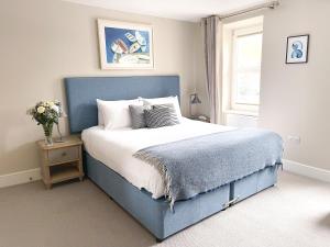 Un dormitorio con una cama azul y una ventana en Sail Lofts, en Douglas