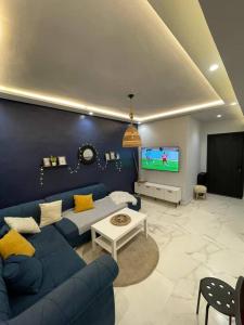 ein Wohnzimmer mit einem blauen Sofa und einem TV in der Unterkunft Appartement Elégant in Casablanca
