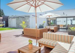 een terras met twee banken en een parasol bij BFRESH Hotel - Padel, Pool & Fitness - Adults Only in Porto