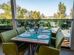 uma mesa de jantar com cadeiras verdes e uma grande janela em Bodrum Beach Resort em Gümbet