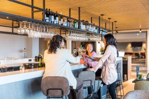 3 Frauen sitzen in einer Bar in einem Restaurant in der Unterkunft Postillion Utrecht Bunnik in Bunnik