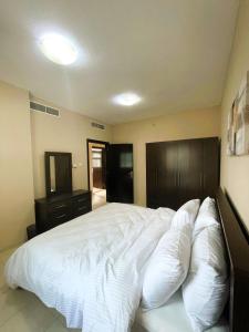 a bedroom with a large bed with white sheets and pillows at Marbella Holiday Homes - Al Nahda 2BHK in Dubai