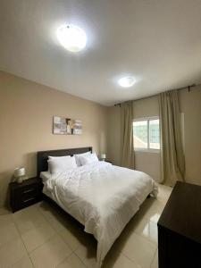Schlafzimmer mit einem Bett mit weißer Bettwäsche und einem Fenster in der Unterkunft Marbella Holiday Homes - Al Nahda 2BHK in Dubai