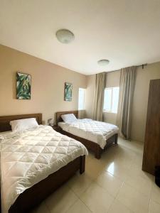 a hotel room with two beds and a window at Marbella Holiday Homes - Al Nahda 2BHK in Dubai