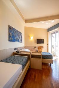 a hotel room with two beds and a tub and a television at Hotel Esperia in Genoa