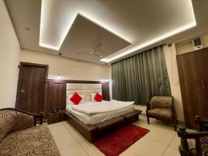 ein Schlafzimmer mit einem Bett mit roten Kissen und einem Stuhl in der Unterkunft Hotel Himgiri in Jammu