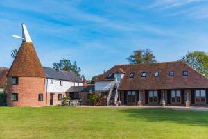 an old church with a windmill on a lawn at The Oast by Bloom Stays in Newenden
