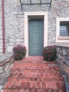 una puerta azul en un edificio de piedra con flores en Relais La Colombara Spa & Wellness, en Travo