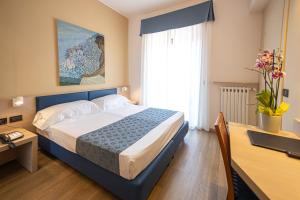 a bedroom with a bed and a desk and a window at Hotel Esperia in Genoa