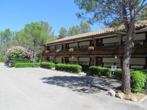 a building with a tree and flowers in front of it at Kyriad Montpellier Nord Parc Euromédecine in Saint-Clément-de-Rivière