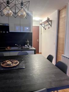 une cuisine avec une table noire, des chaises et une cuisinière dans l'établissement Appartement pied des pistes Puy Saint Vincent (05), à Puy-Saint-Vincent