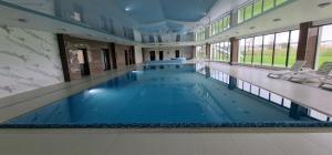 duży basen z niebieską wodą w budynku w obiekcie Baltic Nature Apartment & SPA w Dziwnowie