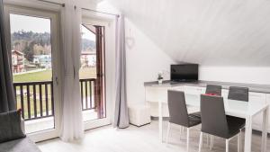 a white dining room with a table and chairs and a balcony at Appartamento Stella in Andalo