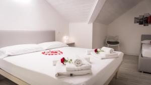 Una cama blanca con toallas y flores. en Appartamento Stella, en Andalo