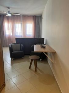 Cette chambre comprend un bureau, une chaise et une table. dans l'établissement Home 4U apt1, just 7km from airport, à Markopoulon