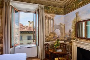 a room with a painting on the wall and a table and a window at Duomo Luxury Florence in Florence