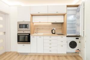 a kitchen with white cabinets and a washer and dryer at Apartment Cinderella in Varna City