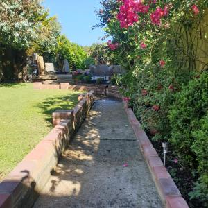 a garden with pink roses and a path with a hedge at House on Costal Village in Peacehaven