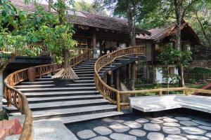 a wooden staircase leading to a building with trees at Earthitects Holiday Experiences,Wayanad in Kalpetta