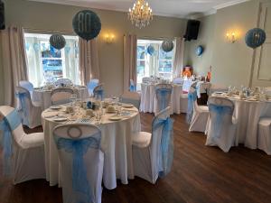 ein Zimmer mit Tischen und Stühlen mit weißen Tischdecken in der Unterkunft Broom Hall Country Hotel in Saham Toney