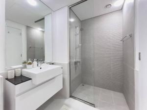a white bathroom with a sink and a shower at StoneTree - Spacious 3 BR in The Pulse C2 in Dubai