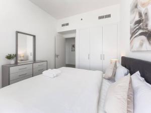a white bedroom with a large bed and a mirror at StoneTree - Spacious 3 BR in The Pulse C2 in Dubai