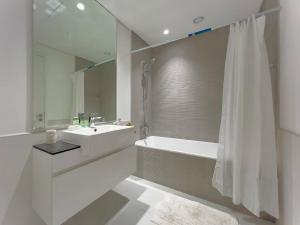 a white bathroom with a tub and a sink at StoneTree - Spacious 3 BR in The Pulse C2 in Dubai