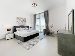a bedroom with a bed and a chair and a window at StoneTree - Spacious 3 BR in The Pulse C2 in Dubai