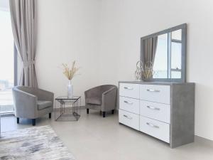 a living room with a dresser and two chairs and a mirror at StoneTree - Spacious 3 BR in The Pulse C2 in Dubai