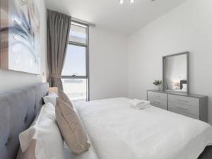 a white bedroom with a bed and a mirror at StoneTree - Spacious 3 BR in The Pulse C2 in Dubai