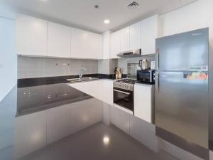a kitchen with white cabinets and a stainless steel refrigerator at StoneTree - Spacious 3 BR in The Pulse C2 in Dubai