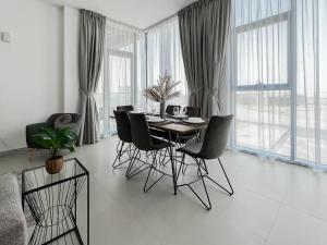 a dining room with a table and chairs and windows at StoneTree - Spacious 3 BR in The Pulse C2 in Dubai