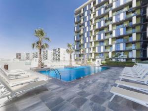 a large apartment building with a swimming pool and lounge chairs at StoneTree - Spacious 3 BR in The Pulse C2 in Dubai