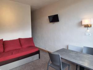 ein Wohnzimmer mit einem roten Sofa und einem Tisch in der Unterkunft Studio Plagne Aime 2000, 1 pièce, 4 personnes - FR-1-181-2585 in Aime La Plagne