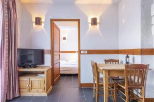 a dining room with a table and a television at Les Aiguilles De Warens in Combloux