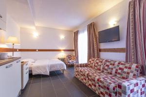 um quarto de hotel com um sofá e uma cama em Les Aiguilles De Warens em Combloux
