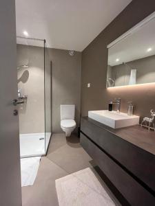 een badkamer met een wastafel, een toilet en een spiegel bij Golfresidenz Davos Platz in Davos
