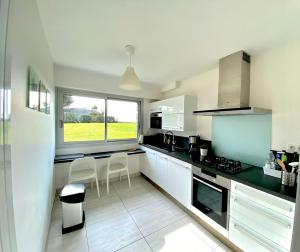 a kitchen with white appliances and a large window at Les Dunes, appartement moderne au bord de l’eau in Larmor-Plage