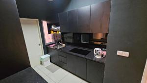 a small kitchen with black cabinets and a sink at Serenestay Cozy Studio @ Southville City in Kajang