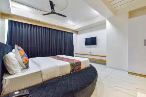 a bedroom with a large bed and a flat screen tv at FabHotel Bliss in Ahmedabad