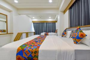 a bedroom with a large bed with a colorful blanket at FabHotel Bliss in Ahmedabad