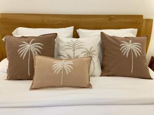 a bed with four pillows with palm trees on it at Villa Solas Legian in Legian +71 photos