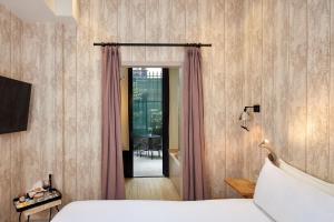 a hotel room with a bed and a door with curtains at Les Plumes Hotel in Paris +30 photos