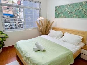 een slaapkamer met een bed met witte lakens en een raam bij Local Me - Exclusive Centre Room in Hai Phong