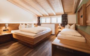 two beds in a room with wooden walls and wood floors at Gsolhof in Rettenberg
