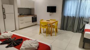 a kitchen with a small table and yellow chairs in a room at Cresta Beach Studios in St. Julianʼs