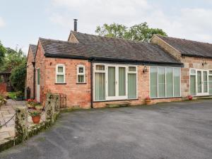 een stenen huis met witte ramen en een oprit bij Abbey View Farm Cottage in Uttoxeter