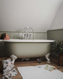 a woman laying in a bath tub in a room at The Swan Inn in Shipton under Wychwood