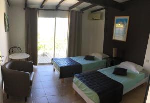 Habitación con 2 camas, silla y ventana en Gîtes et Astrotourisme en Corse, en Erbajolo